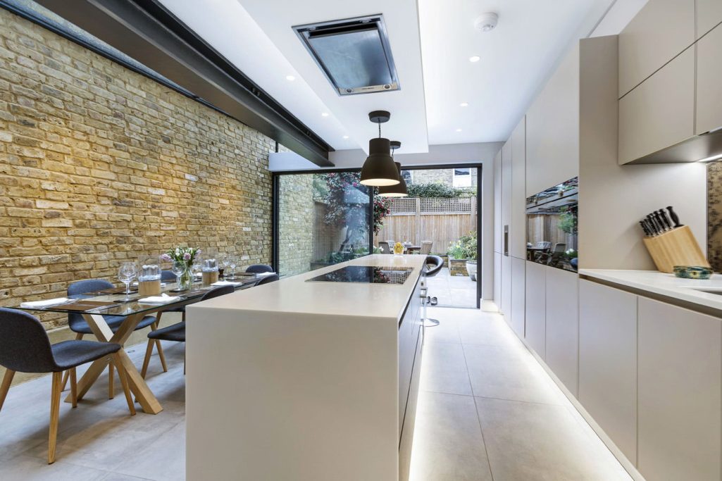 Kitchen Renovation Modern kitchen with a central island, dining area, and large glass doors opening to a garden.