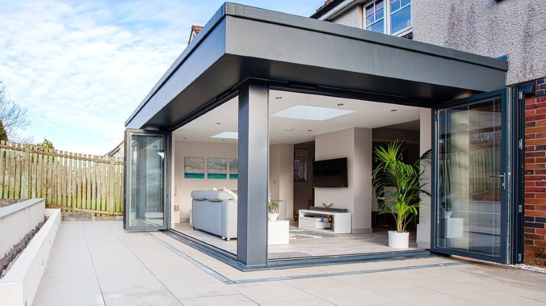 House Extension Modern glass extension of a house with open doors, featuring indoor plants and contemporary décor.