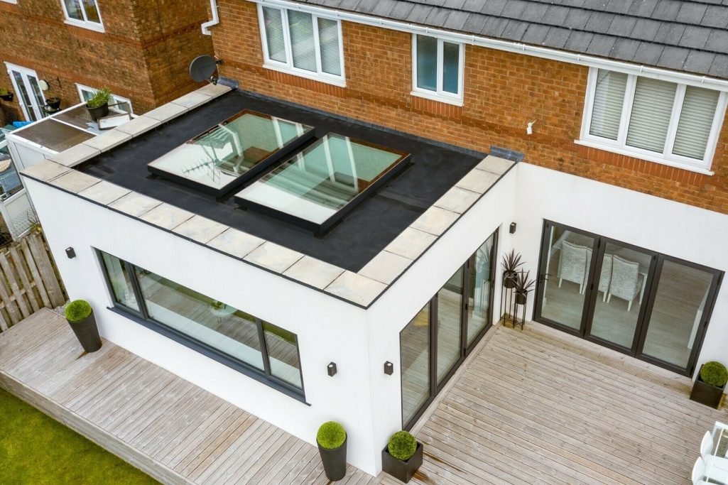 House Extension Modern white house with a flat roof, featuring skylights and a wooden deck.