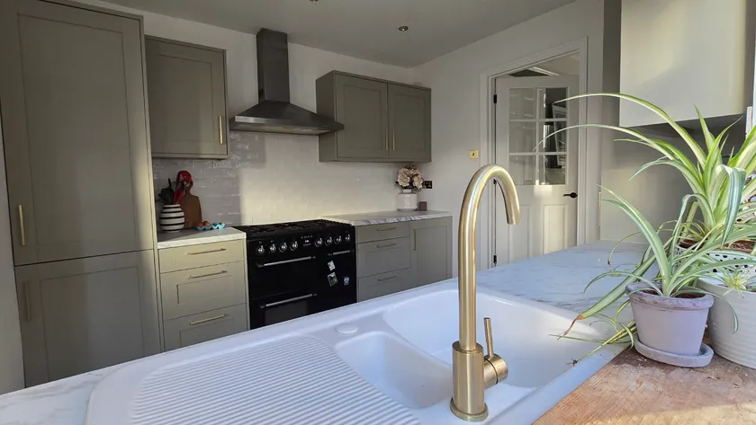 Kitchen Renovation Modern kitchen with grey cabinets, brass tap, and a potted plant on the counter.